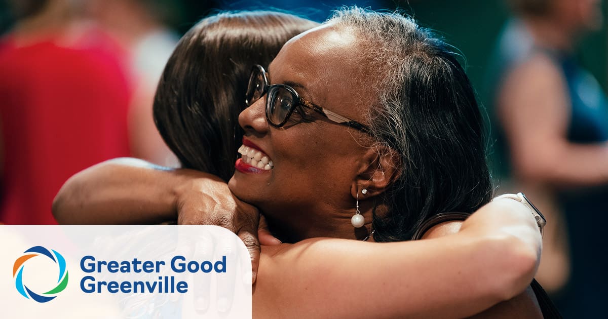 Two women embracing at a Greater Good Greenville event